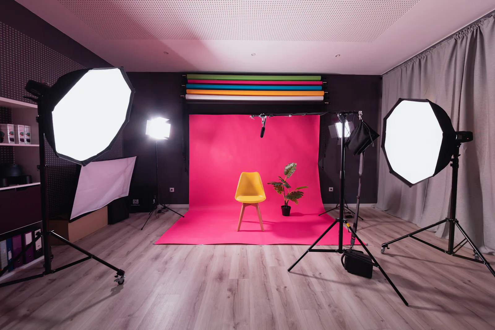 Studio photo avec fond rose, chaise et éclairages